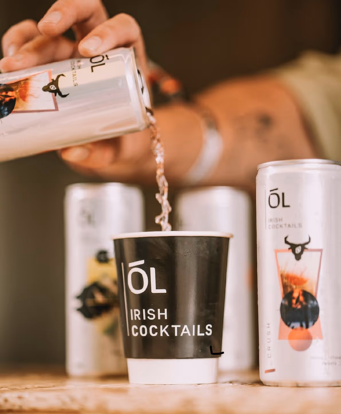 A man pouring a can of Ól Irish Cocktails into a paper cup
